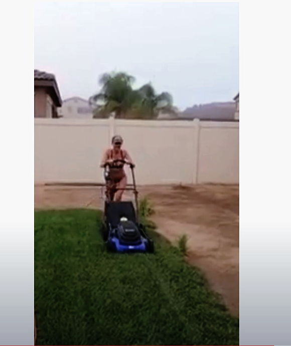 Woman in bikini use electric lawn mower to cut grass